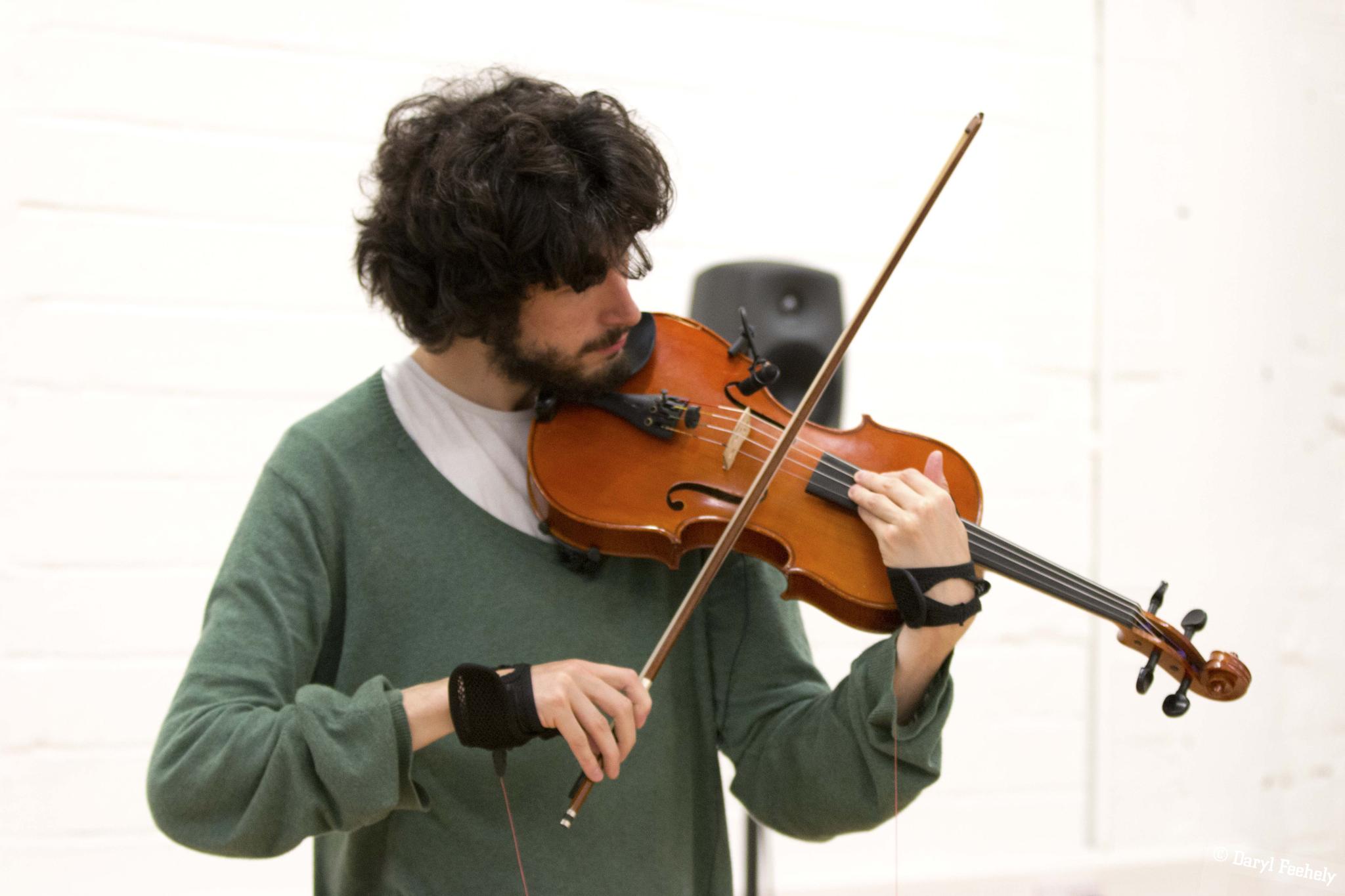 person playing viola with strings attached to their wrists 
